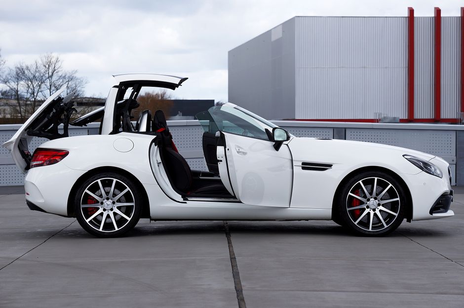 White convertible sports car with its roof raised on an urban rooftop.